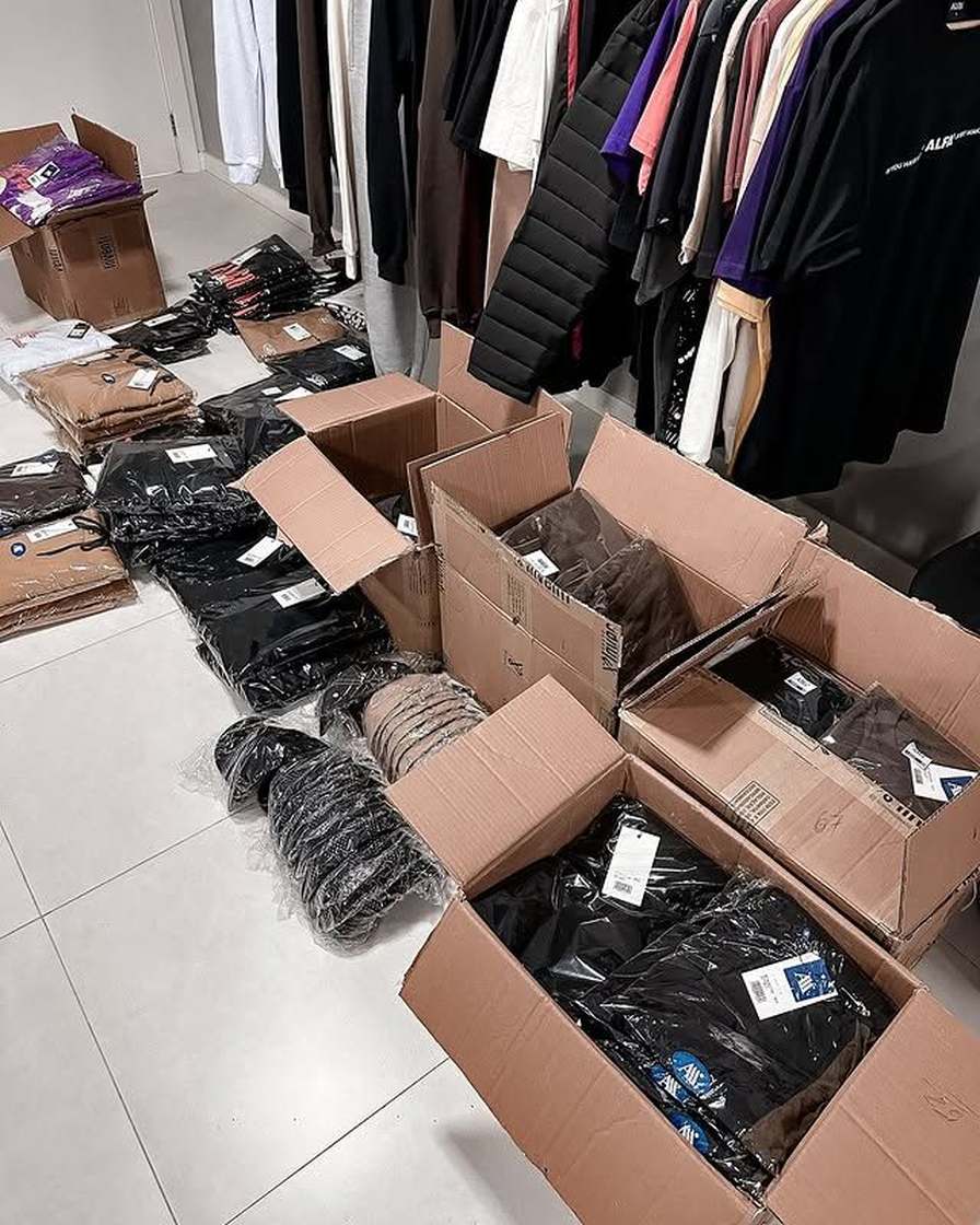 Estoque de roupas embaladas prontas para revenda — caixas e cabides no galpão.
